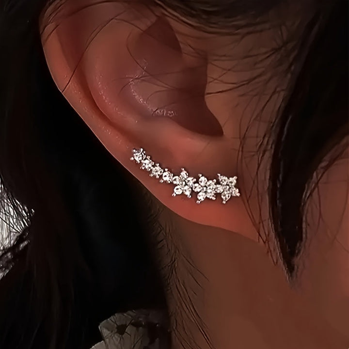 Veda Bremen timeless floral earrings featuring delicate flower designs in gold-tone metal, close-up view of the jewelry.