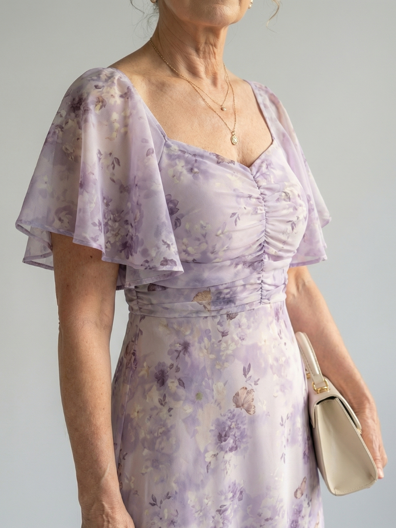 Veda Bremen Vaelis mid-length dress with flutter sleeves, flowing fabric, and elegant design, displayed on a hanger.
