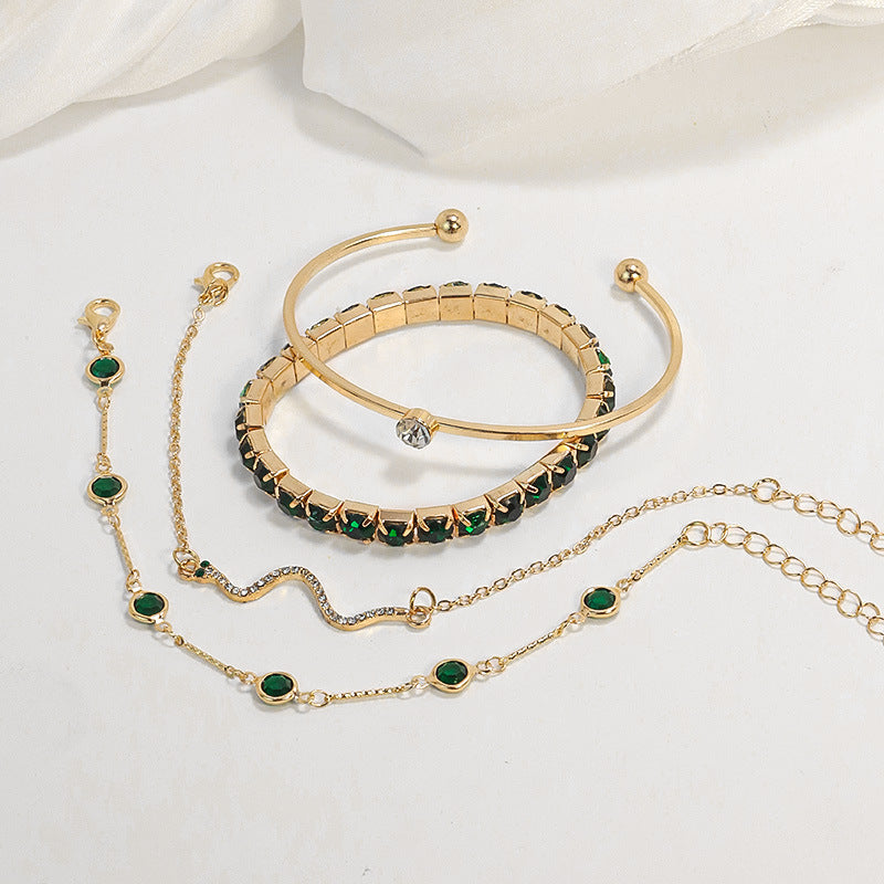 Gold and emerald bracelet set by Veda Bremen featuring elegant gemstone designs on a jewelry display.