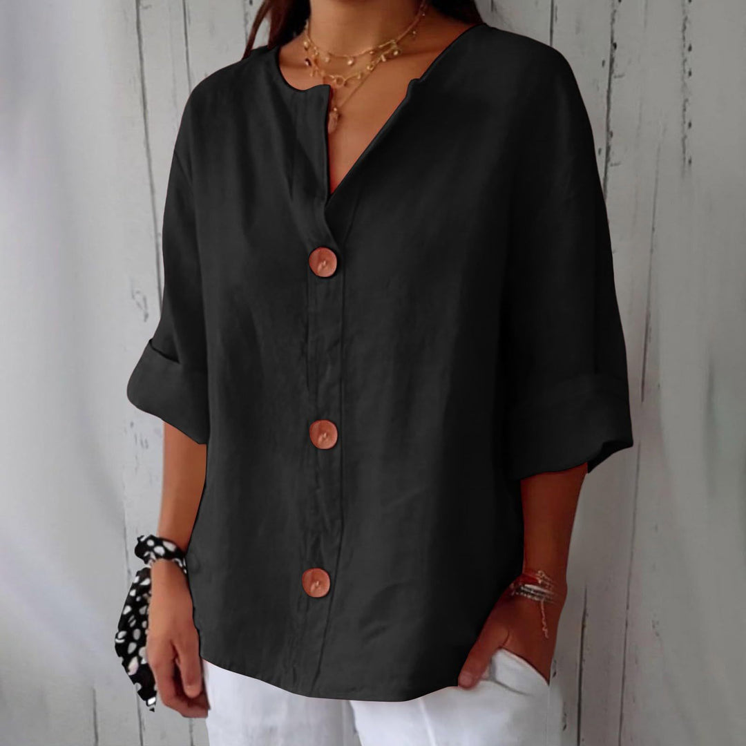 Black Leah minimalist blouse by Veda Bremen, shown on a hanger with clean, simple fabric and subtle design details.