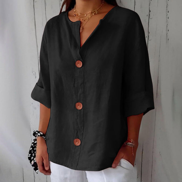 Black Leah minimalist blouse by Veda Bremen, shown on a hanger with clean, simple fabric and subtle design details.