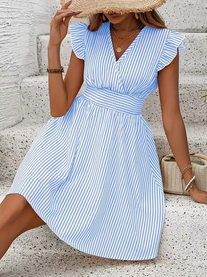 Veda Bremen ruffled striped dress with a flowy silhouette, featuring vertical and horizontal stripe patterns, on a model.