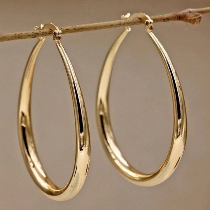 Vintage gold earrings by Veda Bremen featuring elegant gold loops and intricate detailing, displayed on a neutral background.