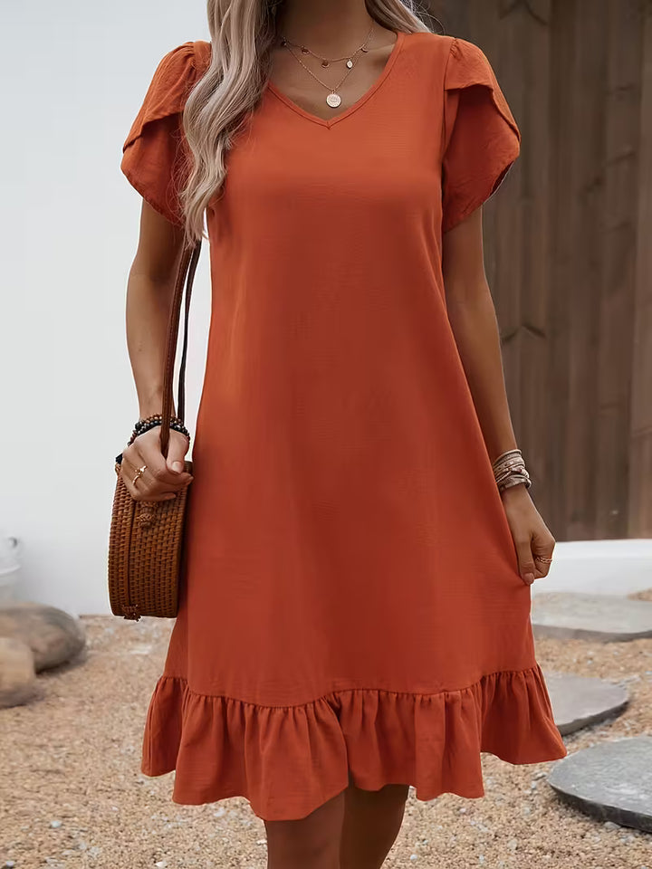 Orange Veda Bremen V-neck dress displayed on a hanger, showcasing its vibrant color and elegant V-shaped neckline.